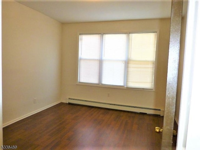 unfurnished room featuring baseboard heating, wood finished floors, and baseboards