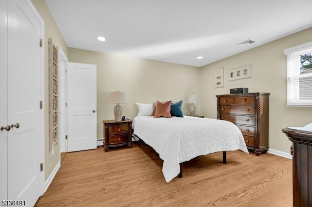 bedroom with a baseboard radiator and light hardwood / wood-style floors