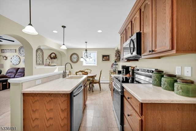 kitchen featuring a kitchen island with sink, hanging light fixtures, sink, and appliances with stainless steel finishes