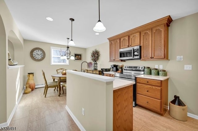 kitchen with a chandelier, a baseboard radiator, appliances with stainless steel finishes, pendant lighting, and a kitchen island with sink