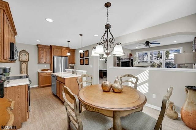 dining space featuring sink, ceiling fan, and light wood-type flooring