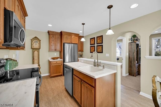 kitchen with stainless steel appliances, decorative light fixtures, sink, and light wood-type flooring