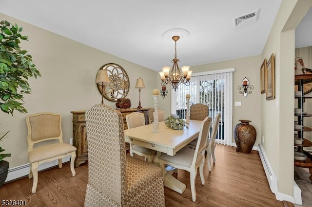 dining room with wood-type flooring, a chandelier, and a baseboard heating unit