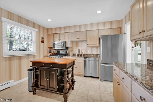 kitchen with sink, butcher block counters, a baseboard heating unit, stainless steel appliances, and light brown cabinetry