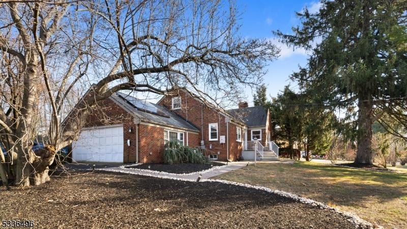 view of side of property with a garage, brick siding, and a chimney