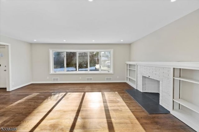 unfurnished living room with dark hardwood / wood-style flooring and a brick fireplace