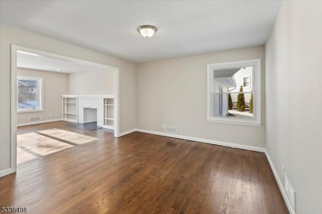 unfurnished living room with a brick fireplace and dark wood-type flooring