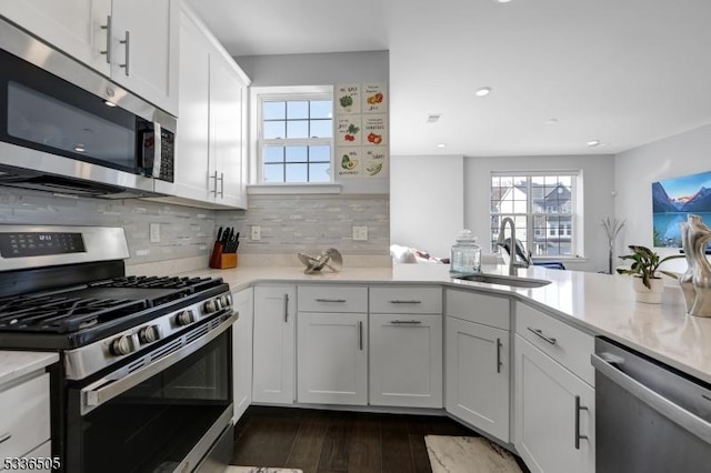 kitchen with dark hardwood / wood-style floors, tasteful backsplash, sink, white cabinets, and stainless steel appliances