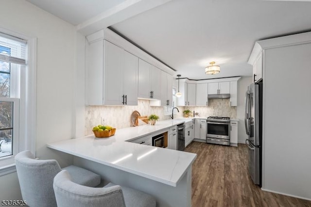 kitchen featuring appliances with stainless steel finishes, decorative light fixtures, white cabinets, and kitchen peninsula