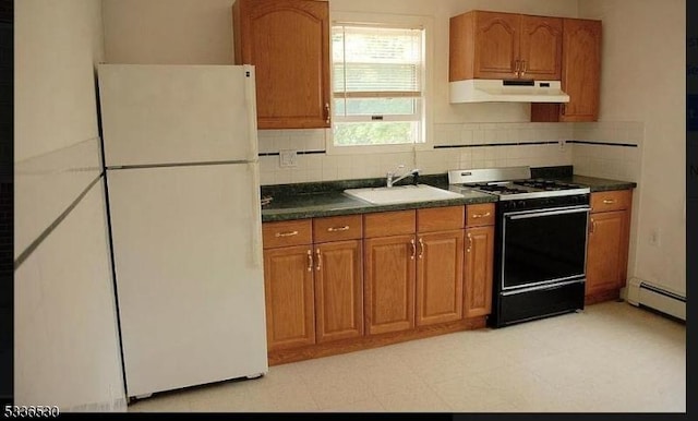 kitchen with sink, gas stove, white refrigerator, baseboard heating, and decorative backsplash