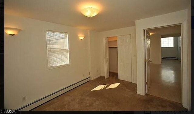 unfurnished bedroom featuring dark colored carpet, a closet, and a baseboard heating unit