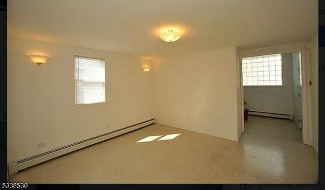 unfurnished room with a baseboard heating unit