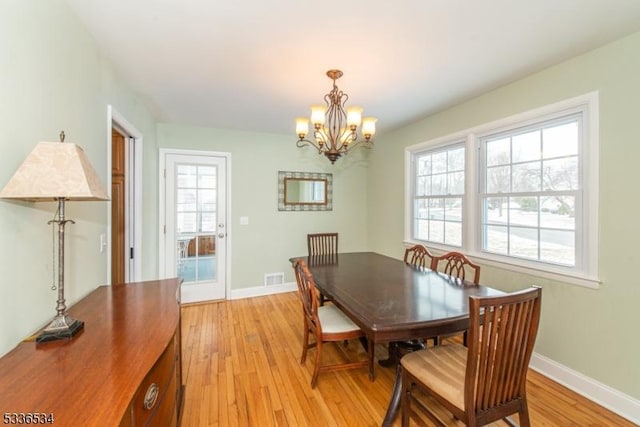 dining space featuring light hardwood / wood-style flooring and a chandelier