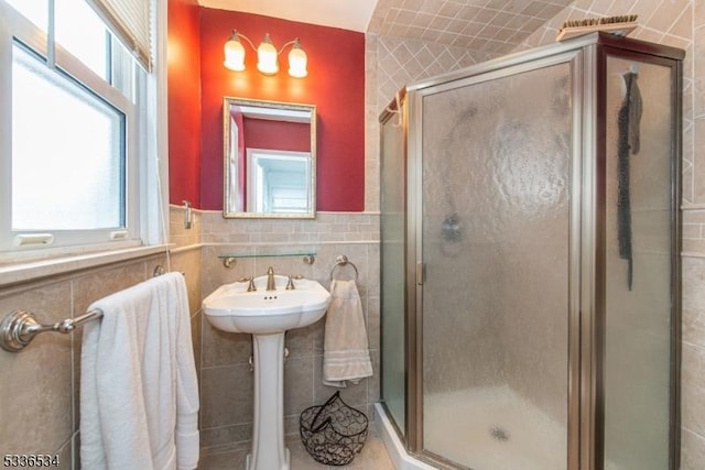 bathroom with tile walls, sink, and a shower with door