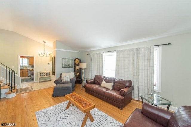 living room with lofted ceiling, a notable chandelier, and light wood-type flooring