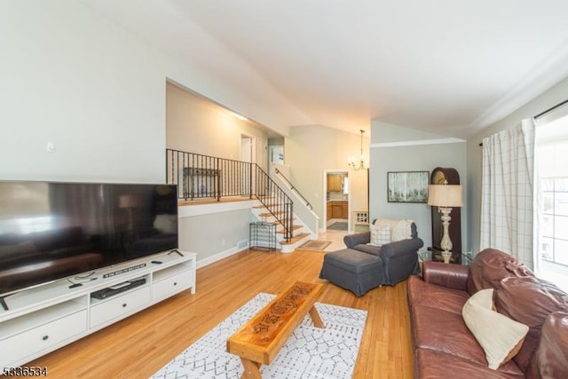 living room with an inviting chandelier, lofted ceiling, and light hardwood / wood-style floors