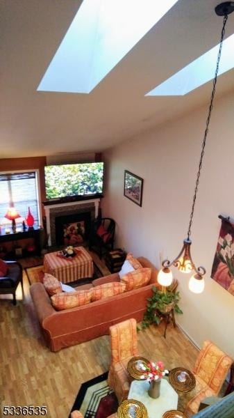 living room featuring wood-type flooring and vaulted ceiling with skylight