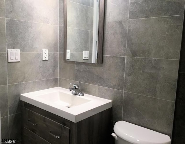 bathroom featuring vanity, toilet, tile walls, and backsplash