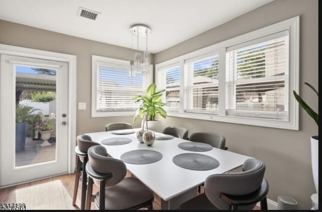 dining room with plenty of natural light, an inviting chandelier, and light hardwood / wood-style floors