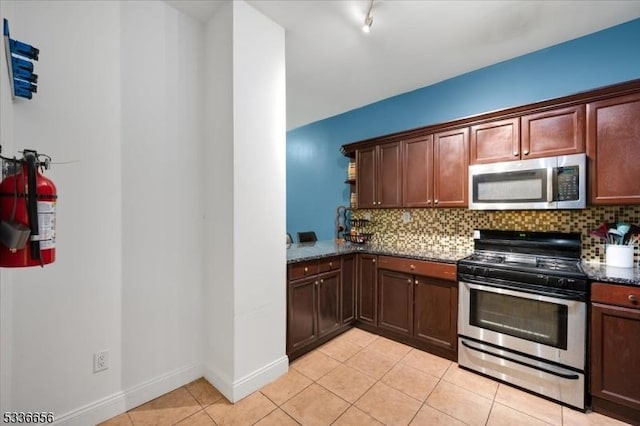 kitchen featuring dark stone countertops, backsplash, light tile patterned floors, and appliances with stainless steel finishes