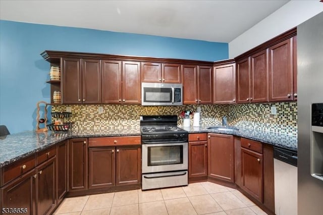 kitchen featuring sink, backsplash, stainless steel appliances, light tile patterned flooring, and dark stone counters