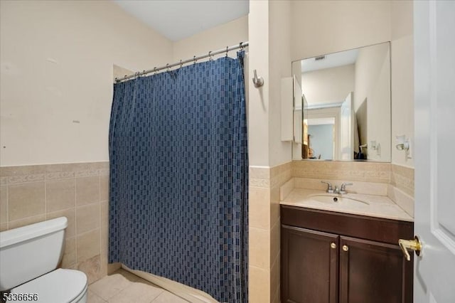 bathroom with curtained shower, tile walls, vanity, toilet, and tile patterned floors