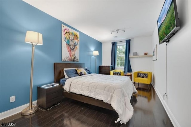 bedroom with rail lighting and hardwood / wood-style floors