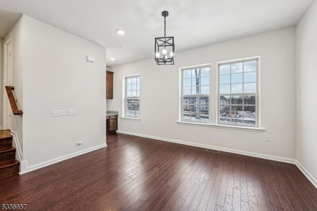 unfurnished dining area featuring a chandelier and dark hardwood / wood-style flooring