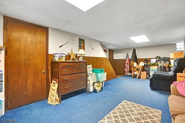 playroom featuring carpet floors, a paneled ceiling, and wood walls