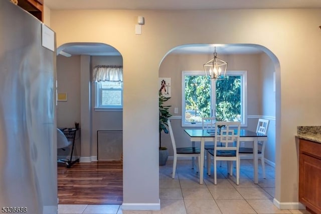 tiled dining room with an inviting chandelier