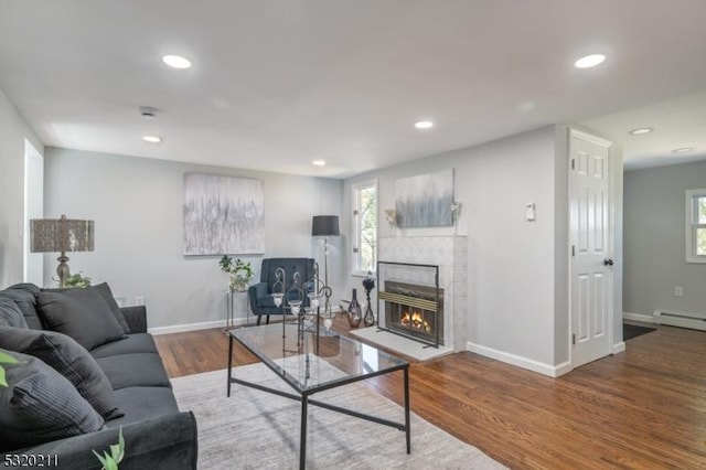 living room featuring baseboard heating, plenty of natural light, and hardwood / wood-style floors