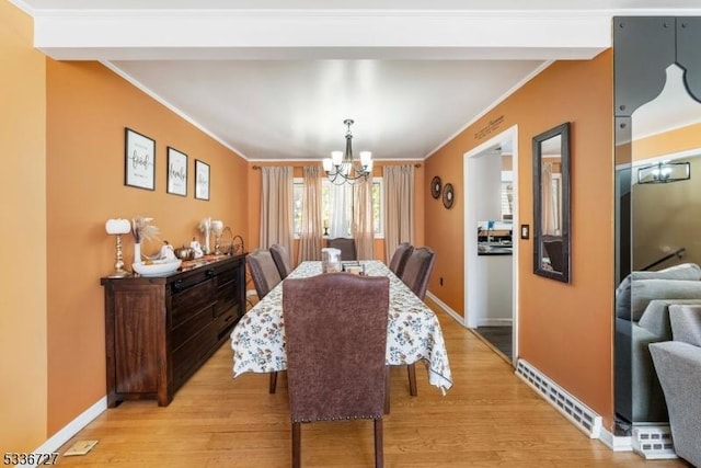 dining area featuring ornamental molding, an inviting chandelier, and light hardwood / wood-style flooring