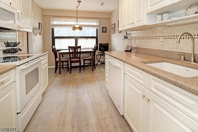 kitchen featuring sink, white cabinets, hanging light fixtures, light stone countertops, and white appliances