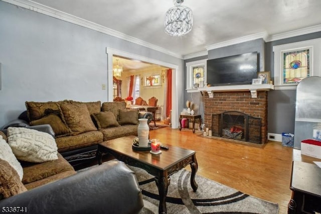 living room featuring an inviting chandelier, hardwood / wood-style flooring, a fireplace, and crown molding