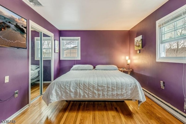 bedroom with baseboard heating and wood-type flooring