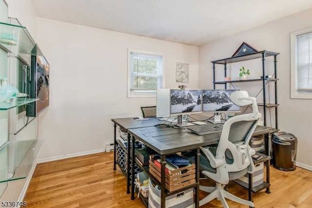 home office featuring baseboard heating, plenty of natural light, and light hardwood / wood-style flooring