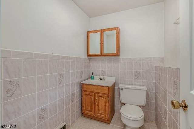 bathroom featuring vanity, tile patterned floors, tile walls, and toilet