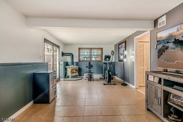 exercise area featuring light tile patterned floors and a wood stove