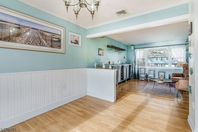 interior space with hardwood / wood-style flooring, crown molding, a chandelier, and beamed ceiling