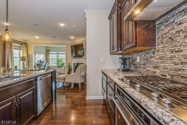 kitchen featuring appliances with stainless steel finishes, range hood, light stone countertops, decorative backsplash, and decorative light fixtures