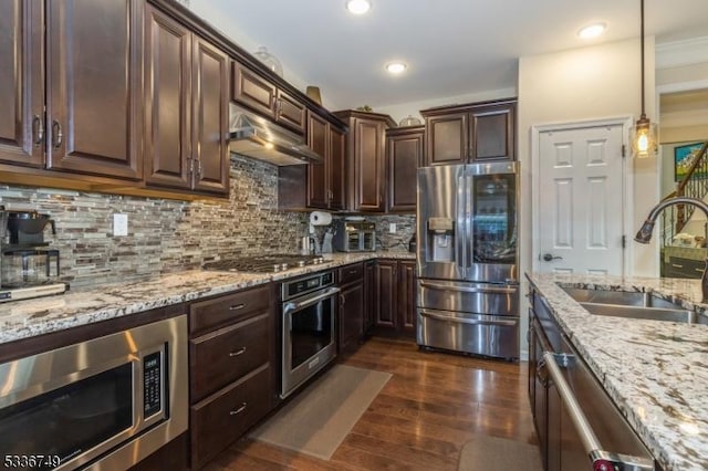 kitchen featuring appliances with stainless steel finishes, decorative light fixtures, tasteful backsplash, sink, and dark brown cabinetry