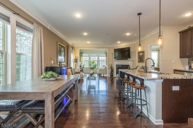 kitchen featuring pendant lighting, sink, a breakfast bar, a kitchen island with sink, and dark brown cabinets