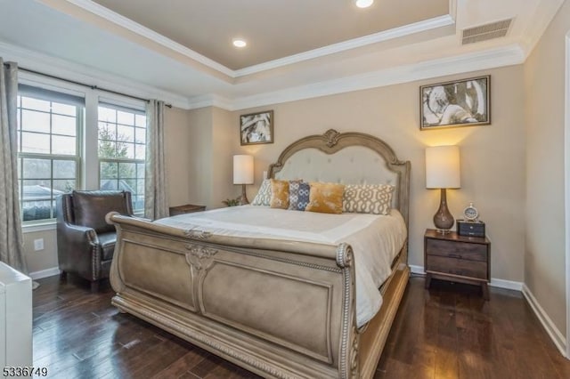 bedroom with ornamental molding, dark wood-type flooring, and a tray ceiling