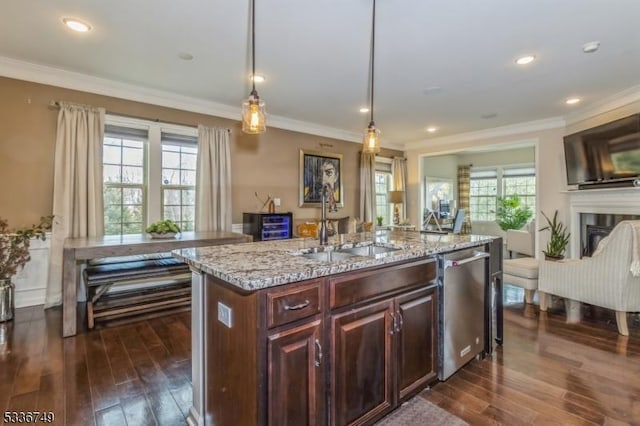 kitchen with pendant lighting, a wealth of natural light, a kitchen island with sink, and stainless steel dishwasher