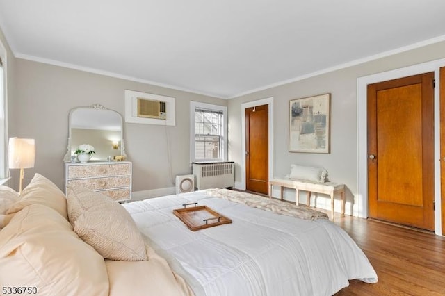 bedroom featuring hardwood / wood-style flooring, crown molding, an AC wall unit, and radiator