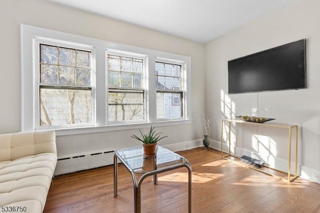 living area featuring hardwood / wood-style floors and a baseboard heating unit