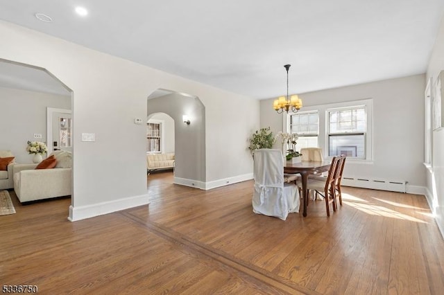 dining area with dark hardwood / wood-style floors, a chandelier, and a baseboard heating unit