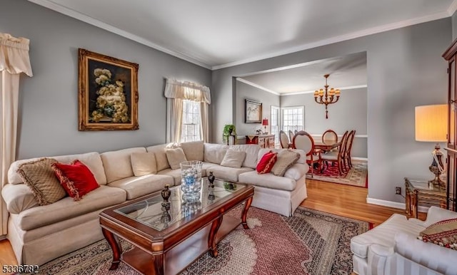 living room featuring wood-type flooring, ornamental molding, and a chandelier