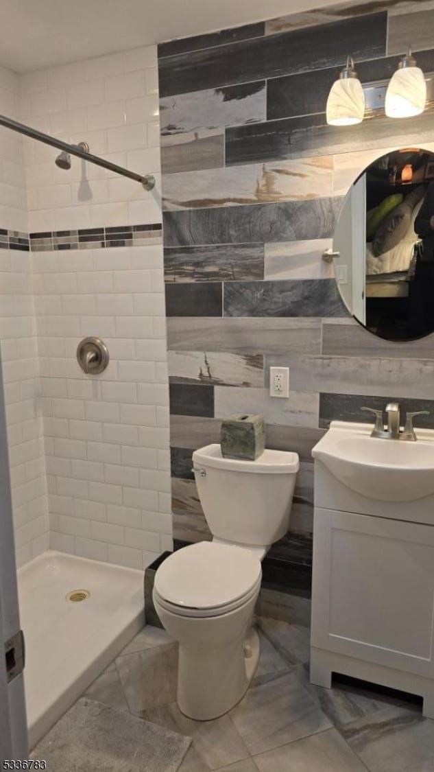 bathroom featuring vanity, toilet, and a tile shower