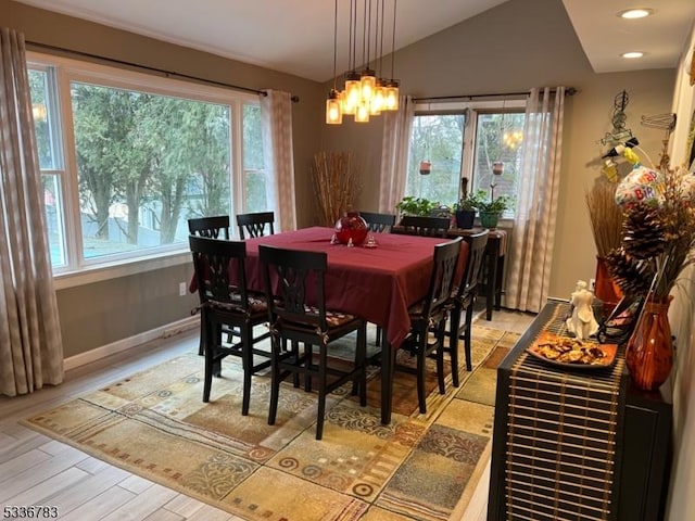 dining space featuring plenty of natural light, lofted ceiling, a chandelier, and light hardwood / wood-style flooring